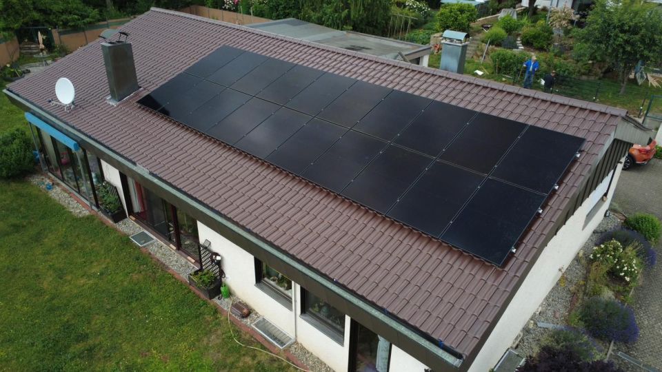 Luftaufnahme eines Bungalows mit einem großen Feld schwarzer Solarmodule